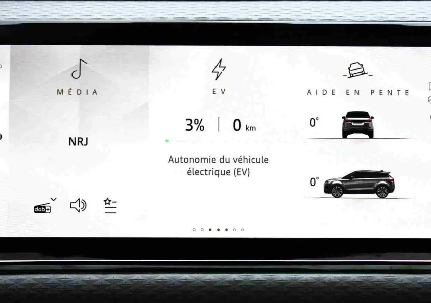 Écran tactile du tableau de bord du Range Rover Evoque 2023 gris métal, affichant l'autonomie électrique et l'aide en pente.