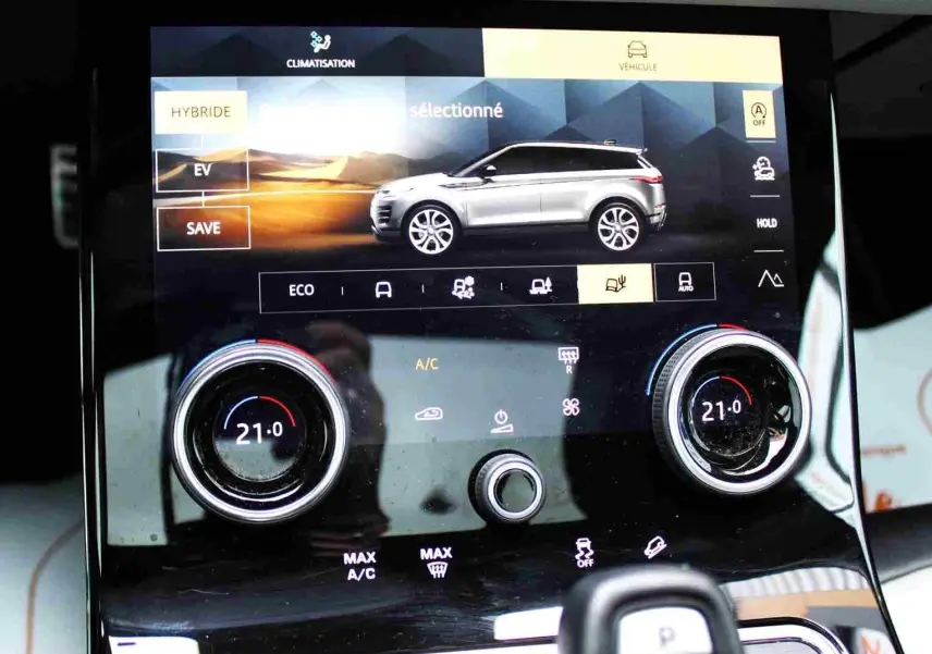Écran tactile intérieur du Range Rover Evoque 2023 gris métal, affichant les réglages climatisation et modes hybrides.