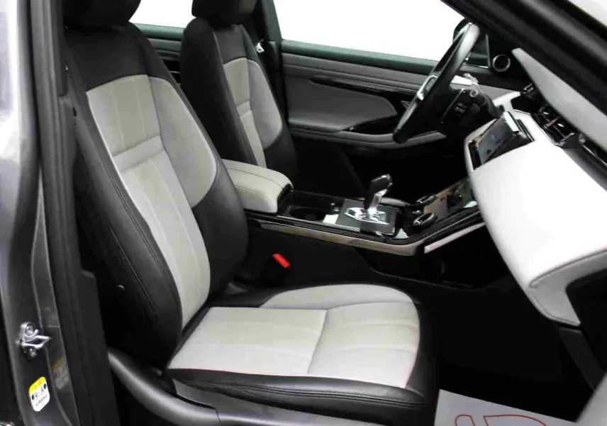 Vue intérieure côté gauche du Range Rover Evoque gris métal 2023, mettant en valeur les sièges bicolores et la console centrale moderne.