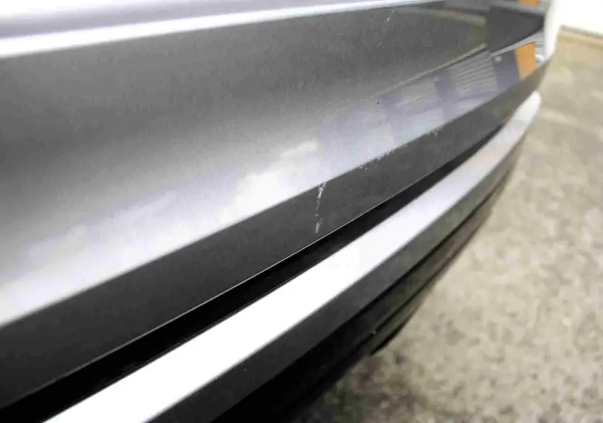 Gros plan sur la partie arrière grise métallisée du Range Rover Evoque 2023, montrant une rayure visible sur la carrosserie.