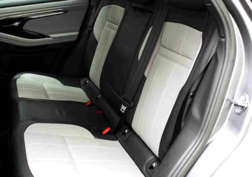 Vue intérieure côté gauche des sièges arrière bicolores noir et blanc du Range Rover Evoque gris métal 2023 hybride rechargeable.