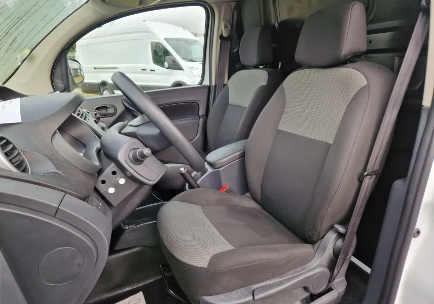Vue intérieure côté conducteur du Renault Kangoo blanc 2019, montrant les sièges avant et le volant.