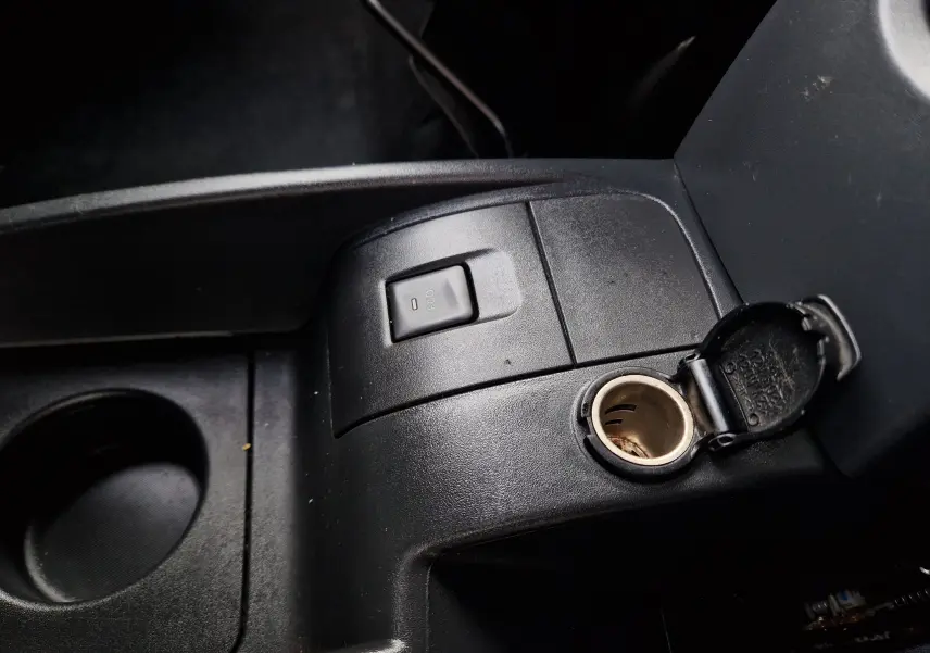 Gros plan sur la console centrale noire du Renault Kangoo blanc, montrant l'interrupteur ECO et la prise 12V ouverte.