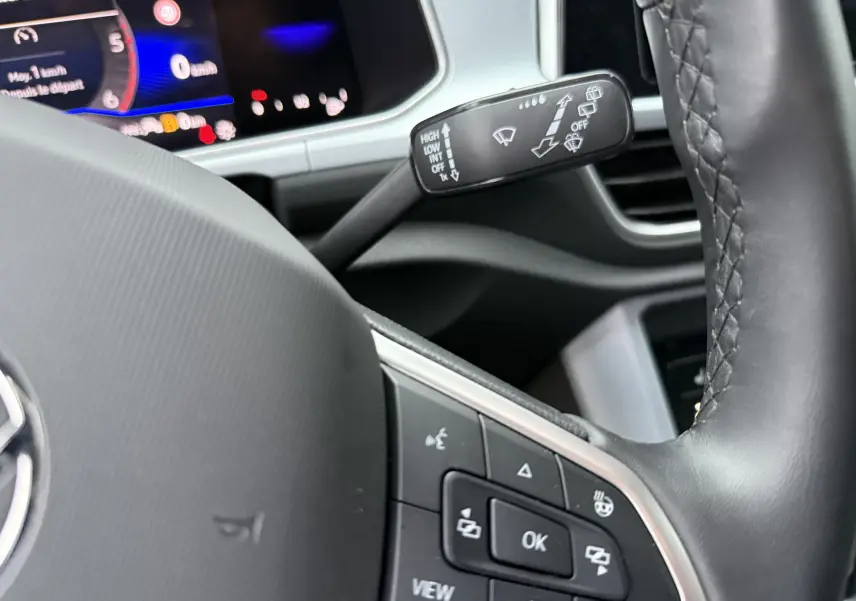 Gros plan sur le volant et les commandes du tableau de bord du Volkswagen T-Roc 2025, intérieur noir moderne.