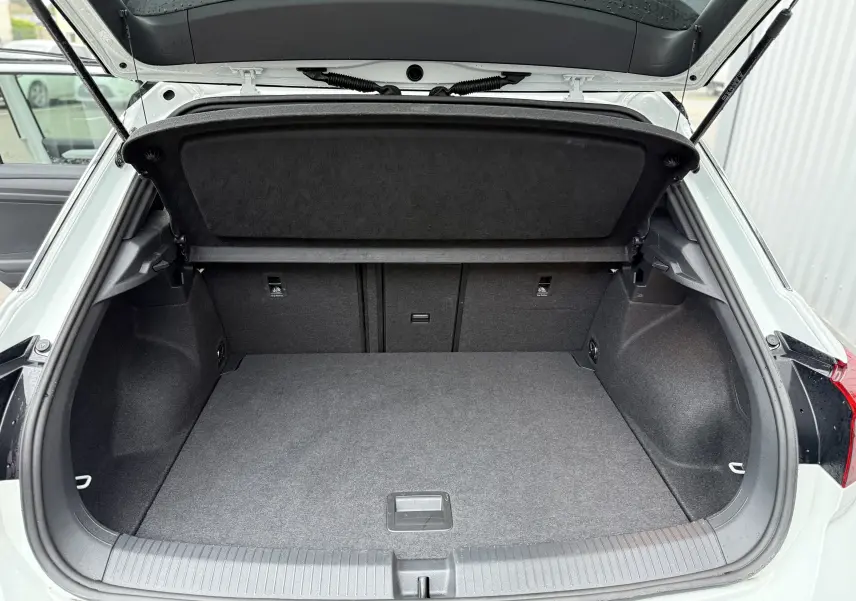 Coffre ouvert vu de l'arrière d'un Volkswagen T-Roc blanc pure avec toit noir, montrant un espace de chargement vide et propre.