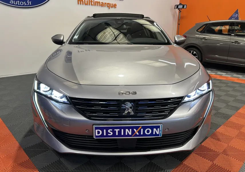 Peugeot 508 SW gris Platinium vue de face avec phares LED allumés et calandre noire distinctive.