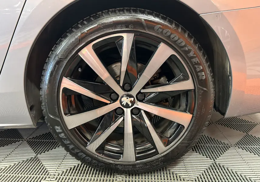 Gros plan sur la roue avant droite d'une Peugeot 508 SW gris Platinium avec jante alliage bicolore et pneu Goodyear.