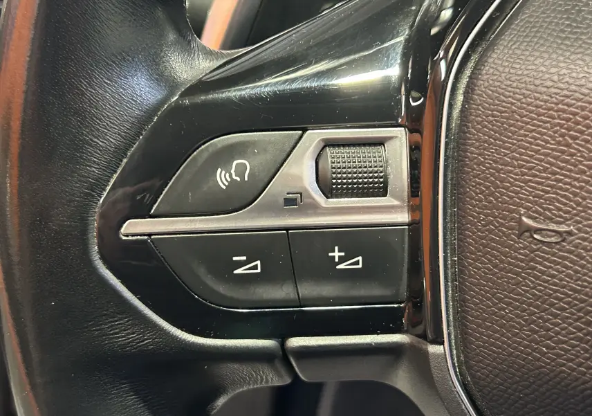Gros plan sur les commandes de volume et de reconnaissance vocale sur le volant en cuir noir du Peugeot 508 SW.