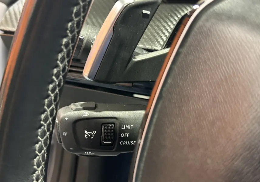 Gros plan sur la commande de régulateur de vitesse au volant cuir noir du Peugeot 508 SW Gris Platinium.