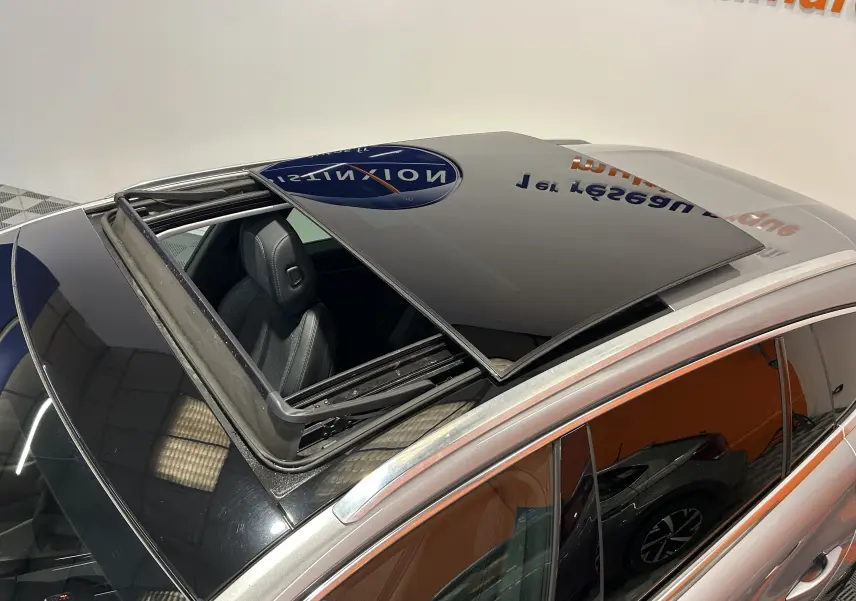 Vue en plongée sur le toit ouvrant ouvert d'un Peugeot 508 SW gris Platinium avec intérieur noir visible.