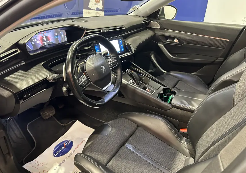 Vue intérieure côté conducteur de la Peugeot 508 SW 2019, montrant le tableau de bord moderne et les sièges en cuir noir.