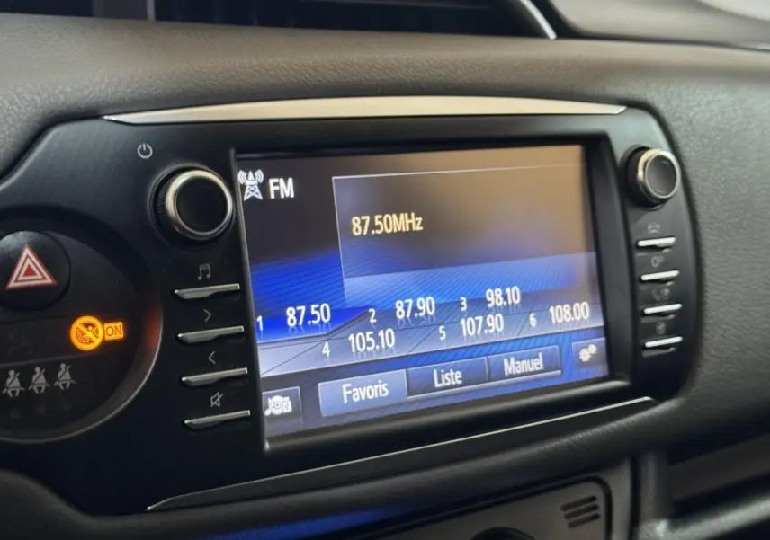 Écran tactile central de la Toyota Yaris 1.5 Hybrid 2019 affichant la radio FM à 87,50 MHz, vue rapprochée intérieure.