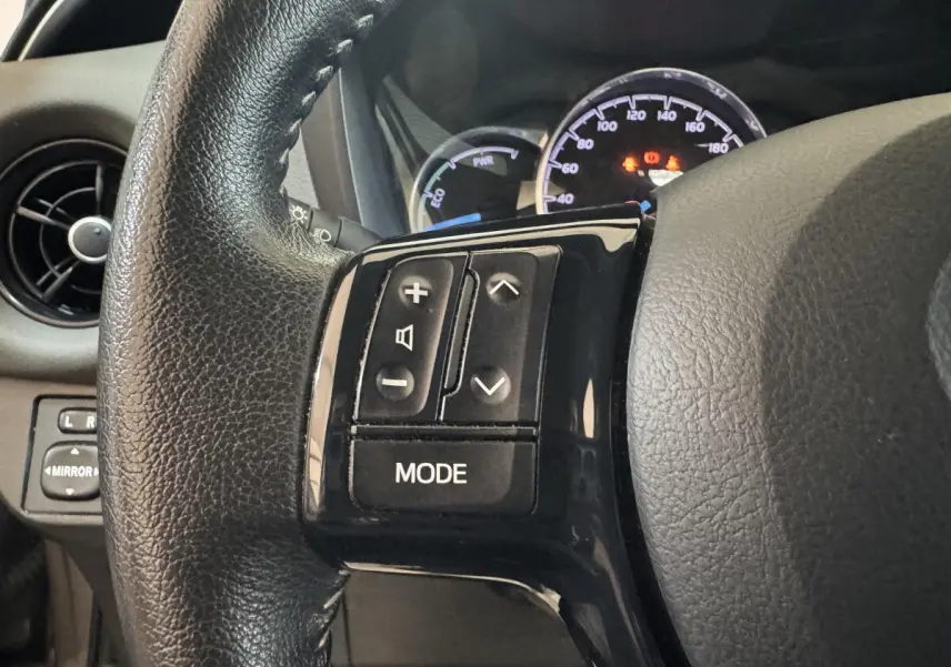 Gros plan sur le volant cuir noir de la Toyota Yaris 2019, avec commandes audio intégrées côté gauche.