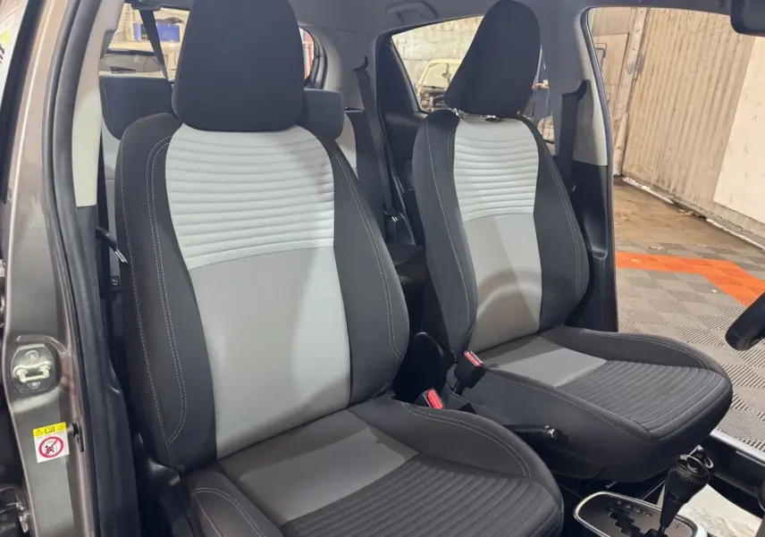 Vue intérieure sur les sièges avant gris clair et foncé de la Toyota Yaris 1.5 Hybrid 2019 avec boîte automatique.
