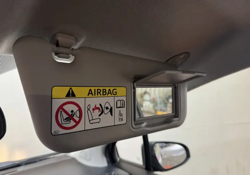 Détail du pare-soleil côté conducteur avec miroir et avertissement airbag dans l’habitacle d’une Toyota Yaris gris foncé.