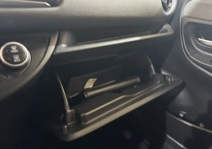 Vue rapprochée de la boîte à gants ouverte côté passager dans une Toyota Yaris 2019 gris foncé, intérieur noir.
