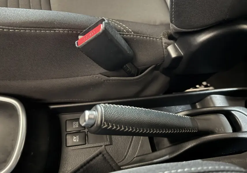 Gros plan sur le frein à main en cuir noir et la ceinture de sécurité grise à l'intérieur de la Toyota Yaris hybride 2019.
