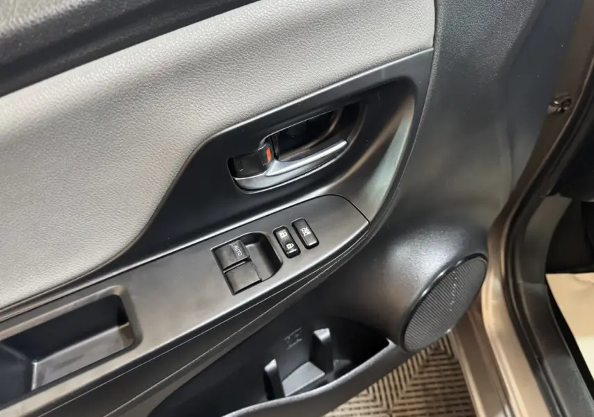Gros plan sur la porte avant gauche de la Toyota Yaris gris foncé, montrant la poignée, les commandes de vitres et haut-parleur.