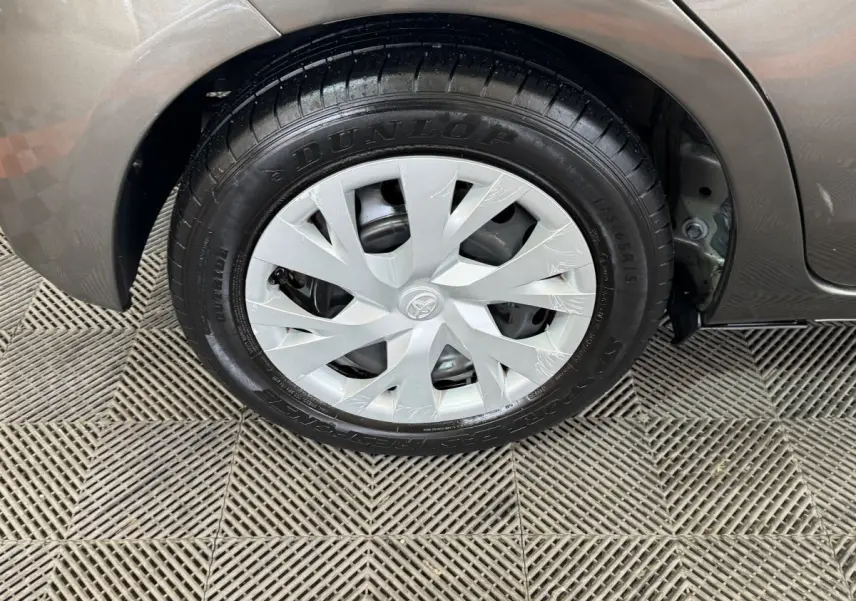 Gros plan sur la roue arrière droite grise foncée d'une Toyota Yaris 1.5 VVT-I Hybrid avec jante en plastique et pneu Dunlop.