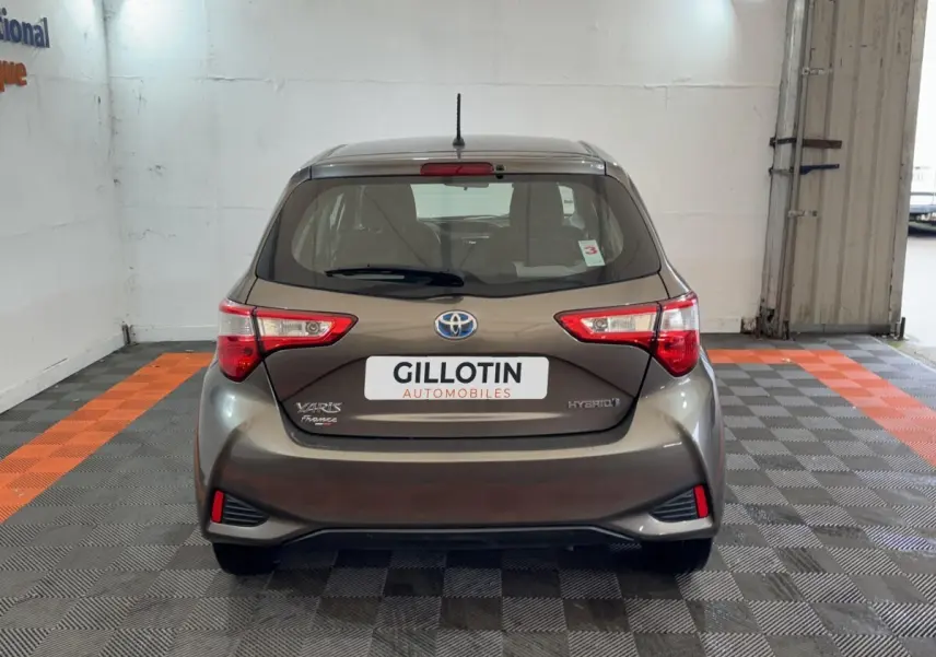 Vue arrière d'une Toyota Yaris 1.5 VVT-I Hybrid gris foncé, avec feux arrière distinctifs et logo Toyota visible.
