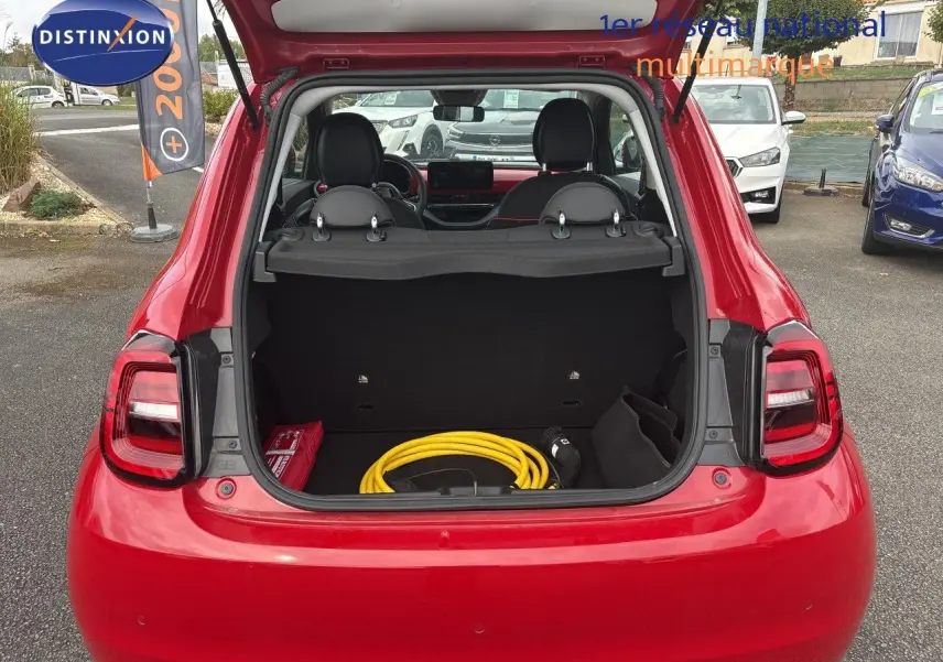 Vue arrière ouverte d'une FIAT 500e rouge 2024 montrant le coffre avec câble de recharge électrique rangé.