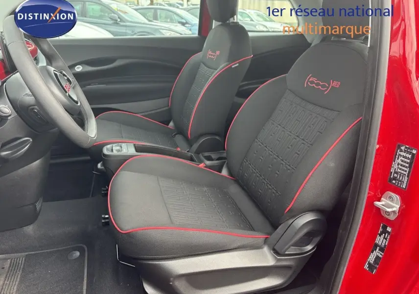Vue intérieure côté conducteur de la FIAT 500e rouge 2024, sièges noirs avec surpiqûres rouges et logo 500 (RED) brodé.