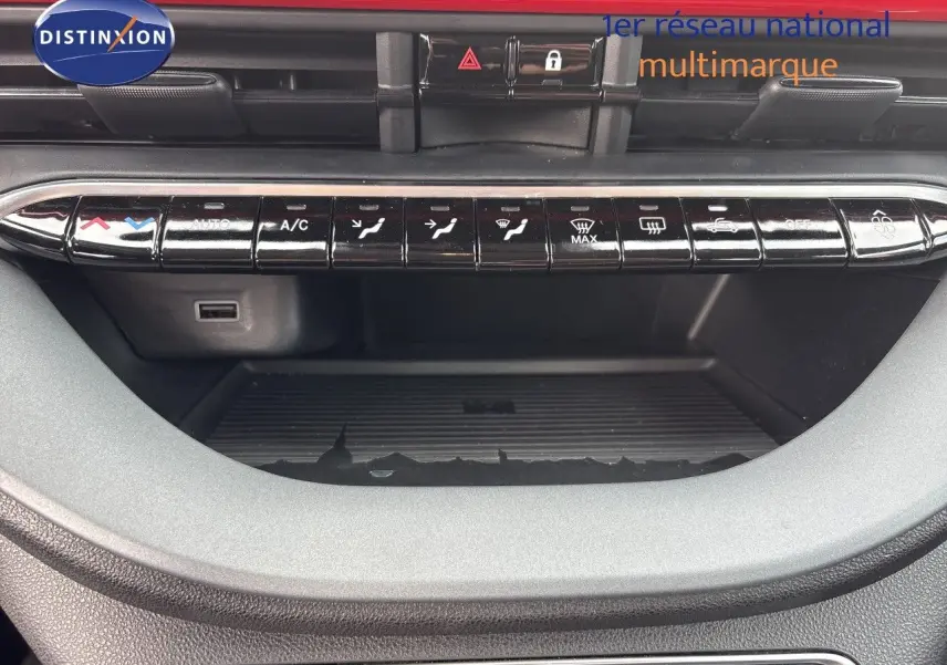 Vue rapprochée de la console centrale de la FIAT 500e rouge 2024, avec commandes climatisation et rangements visibles.