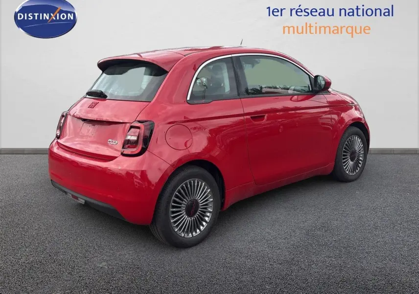 Vue 3/4 arrière droite d'une FIAT 500e rouge électrique 2024 avec jantes classiques et feux arrière foncés.