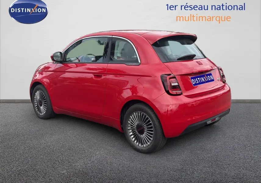 Vue 3/4 arrière droite d'une FIAT 500e rouge électrique 2024 avec jantes classiques et feux arrière sombres.