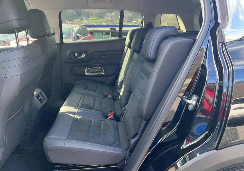 Vue côté droit sur l'intérieur arrière du Citroën C5 Aircross 2025 gris platinium avec sièges en tissu et alcantara noirs.
