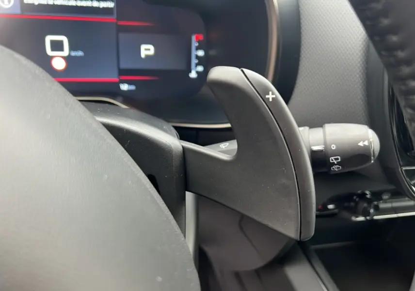 Gros plan sur la palette de passage de vitesses droite du Citroën C5 Aircross Hybrid 2025, tableau de bord numérique en arrière-plan.