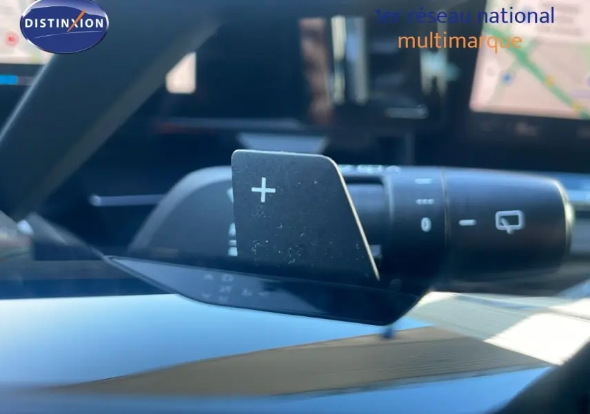 Gros plan sur la palette de changement de vitesse "+" du volant dans l'habitacle du Renault Austral blanc glacier.