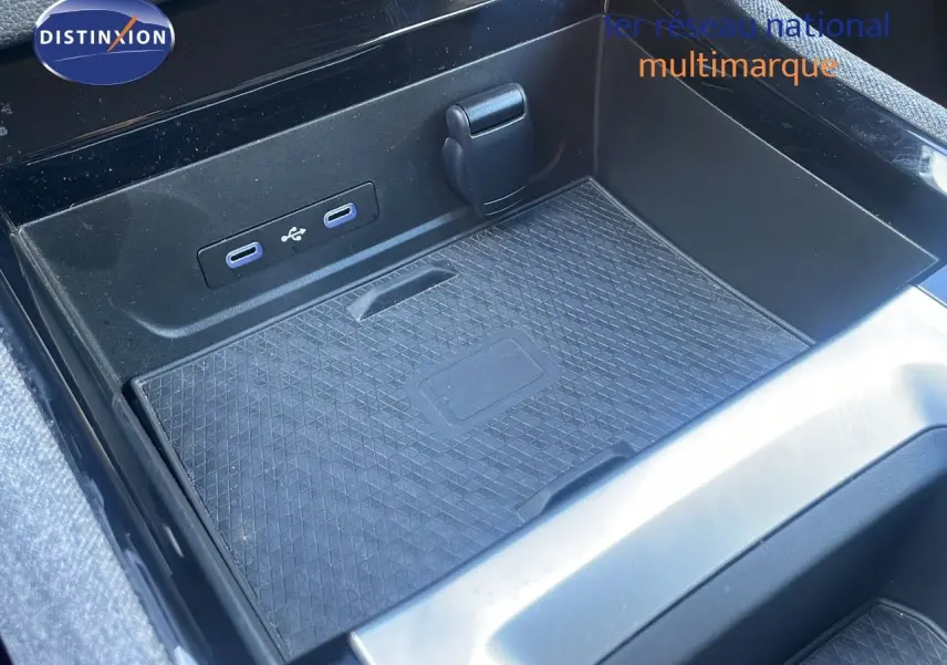 Gros plan sur la console centrale noire du Renault Austral blanc glacier, montrant les ports USB et un espace de rangement.