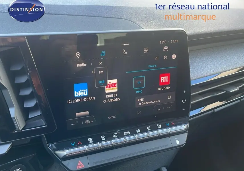 Écran tactile central du tableau de bord du Renault Austral blanc glacier, avec interface radio et commandes climatisation visibles.