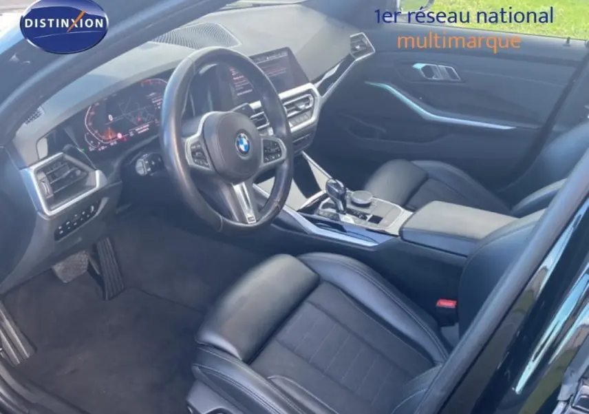 Vue intérieure côté conducteur de la BMW Série 3 G20 noire, avec volant sport, console centrale et sièges en cuir noir.