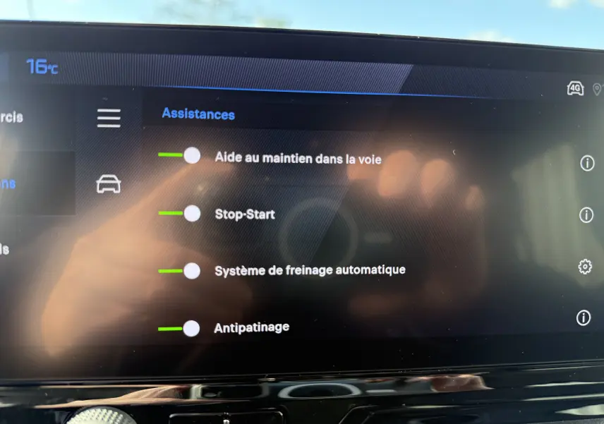 Vue rapprochée de l'écran tactile intérieur du Peugeot Rifter noir Perla Nera, affichant les assistances à la conduite activables.