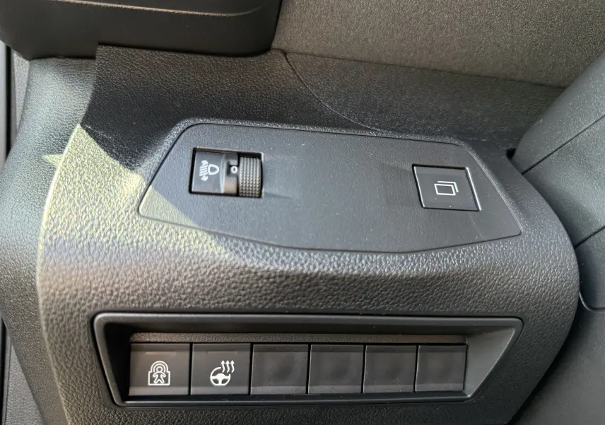 Détail intérieur montrant les commandes de réglage des phares et du volant chauffant sur Peugeot Rifter Allure 2026 noir.