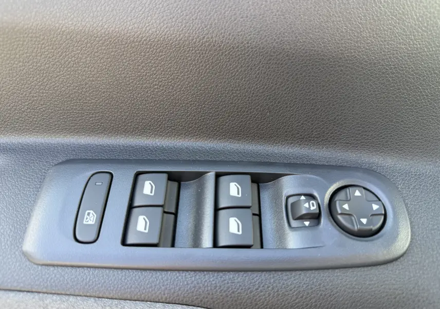Gros plan sur les commandes de lève-vitres et réglage des rétroviseurs côté gauche du Peugeot Rifter noir Perla Nera.