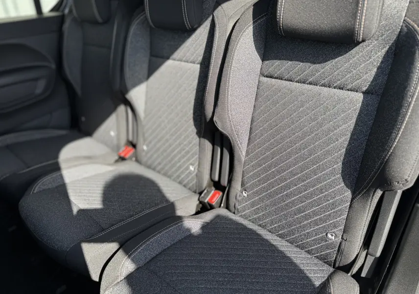 Gros plan sur les sièges arrière en tissu gris foncé du Peugeot Rifter Allure 2026, avec ceinture rouge visible.