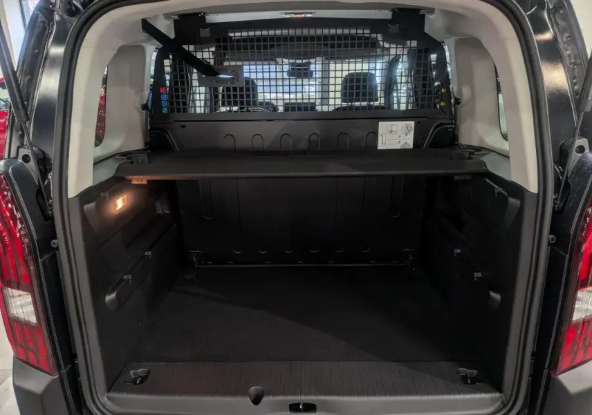 Coffre ouvert du Peugeot Rifter noir Perla Nera, vue arrière montrant la grille de séparation et le plancher de chargement.