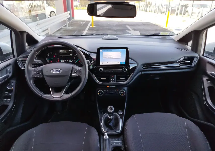Vue intérieure avant de la Ford Fiesta gris lunaire de 2019, montrant le tableau de bord, volant multifonction et écran tactile central.