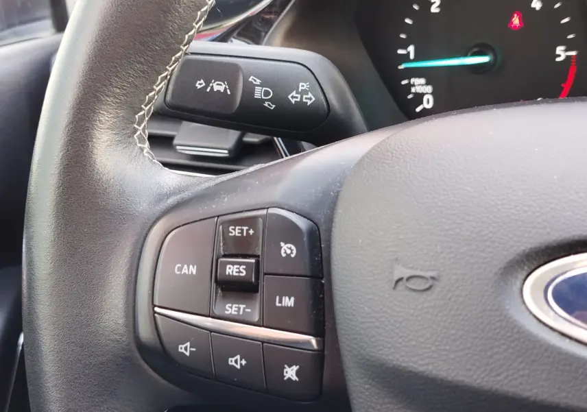 Gros plan sur le volant noir de la Ford Fiesta gris lunaire, montrant les commandes de régulateur de vitesse et les clignotants.