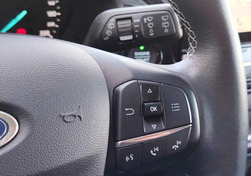 Gros plan sur le volant noir de la Ford Fiesta gris lunaire, avec commandes multifonctions visibles côté droit.