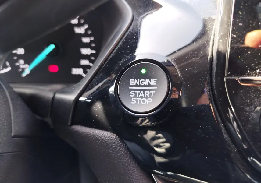 Gros plan sur le bouton moteur start/stop avec témoin vert, tableau de bord partiellement visible d'une Ford Fiesta gris lunaire.