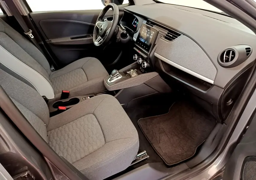 Vue intérieure côté conducteur de la Renault ZOE gris clair, mettant en valeur le tableau de bord et l’écran tactile central.