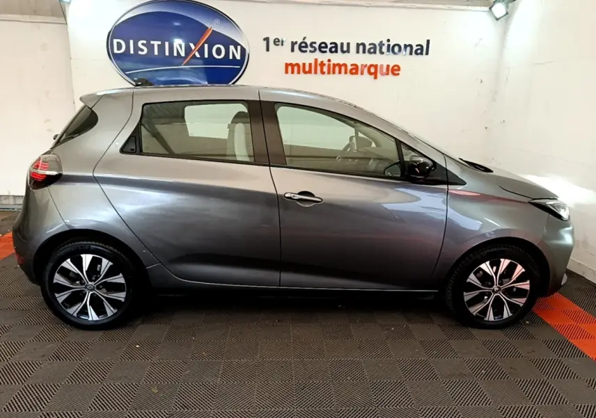Profil droit d'une Renault ZOE gris clair 2022, version evolution R110, avec jantes alliage et vitres teintées.