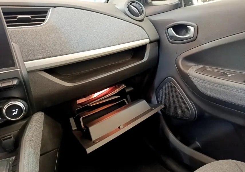 Intérieur de la Renault ZOE gris clair, vue côté passager avec boîte à gants ouverte et tableau de bord texturé.