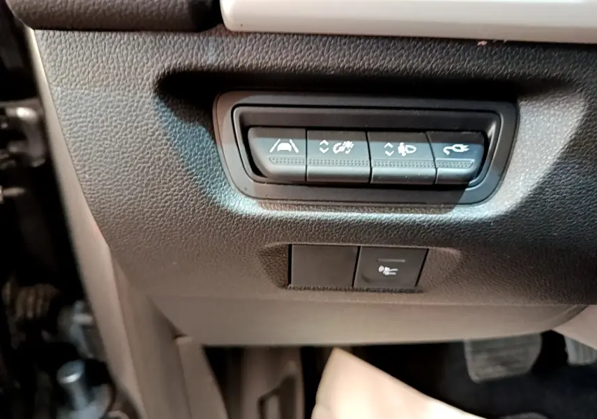 Gros plan sur les boutons de commande situés sous le tableau de bord côté conducteur de la Renault ZOE gris clair électrique.