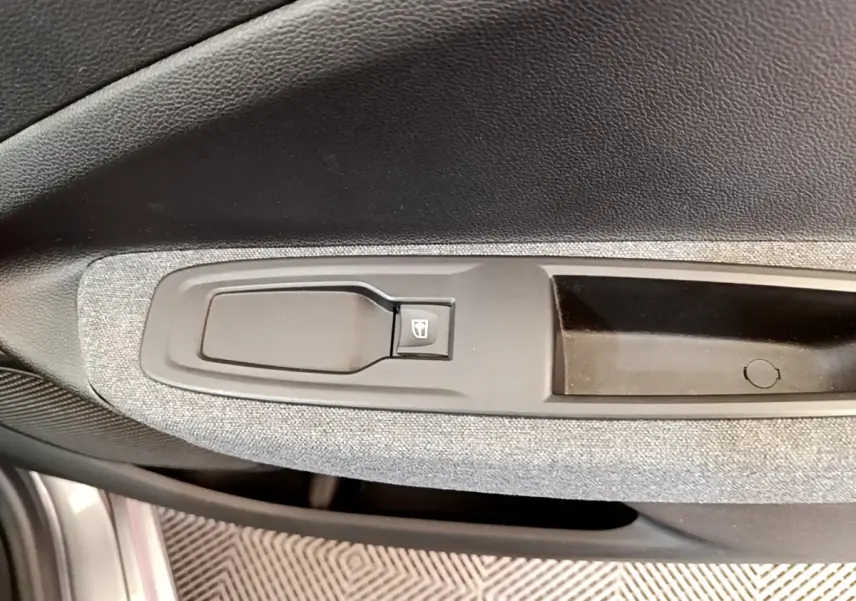 Détail de la commande de lève-vitre côté conducteur sur la porte intérieure grise d’une Renault ZOE électrique 2022.