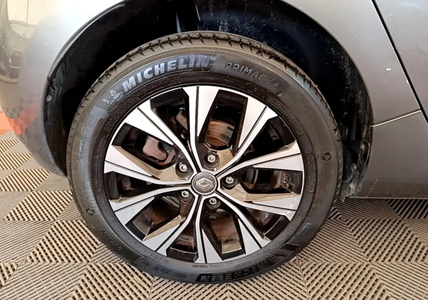 Vue rapprochée de la roue arrière droite d'une Renault ZOE gris clair sur sol à damier.